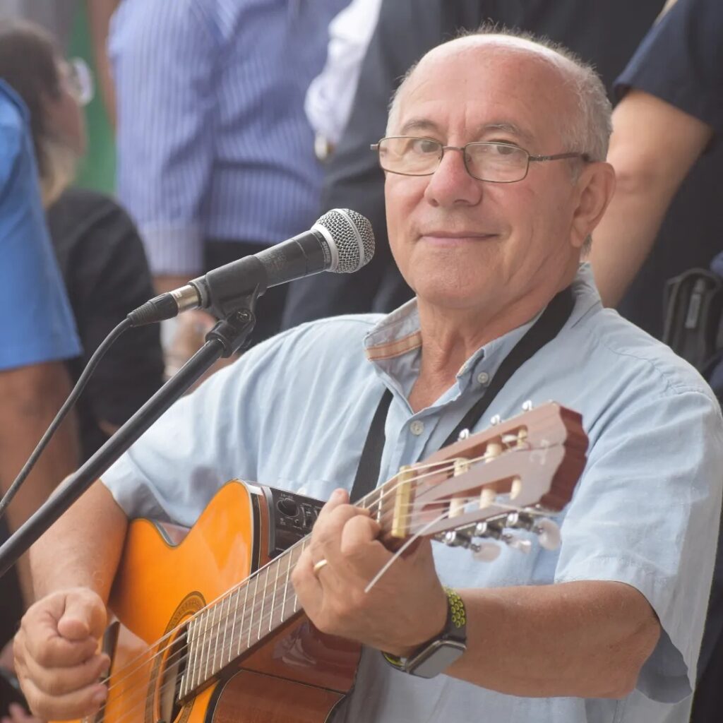 Cantante Luis López sostiene su guitarra al entonar una canción.